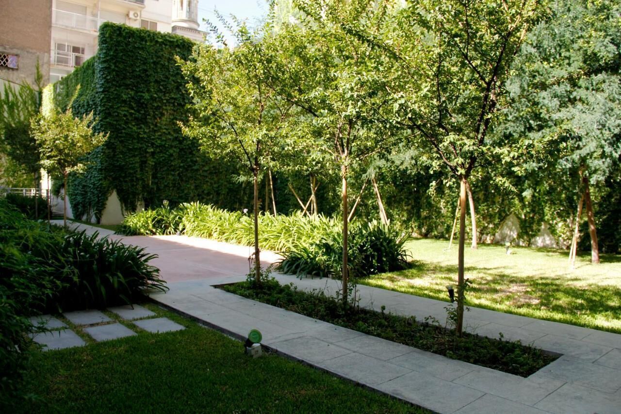 A landscaped garden with a paved walkway, various shrubs, and trees.