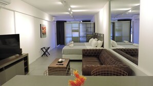 A modern hotel room with a large bed, a sofa, a TV, and a dining area. - Rivadavia Apartments (Buenos Aires)
