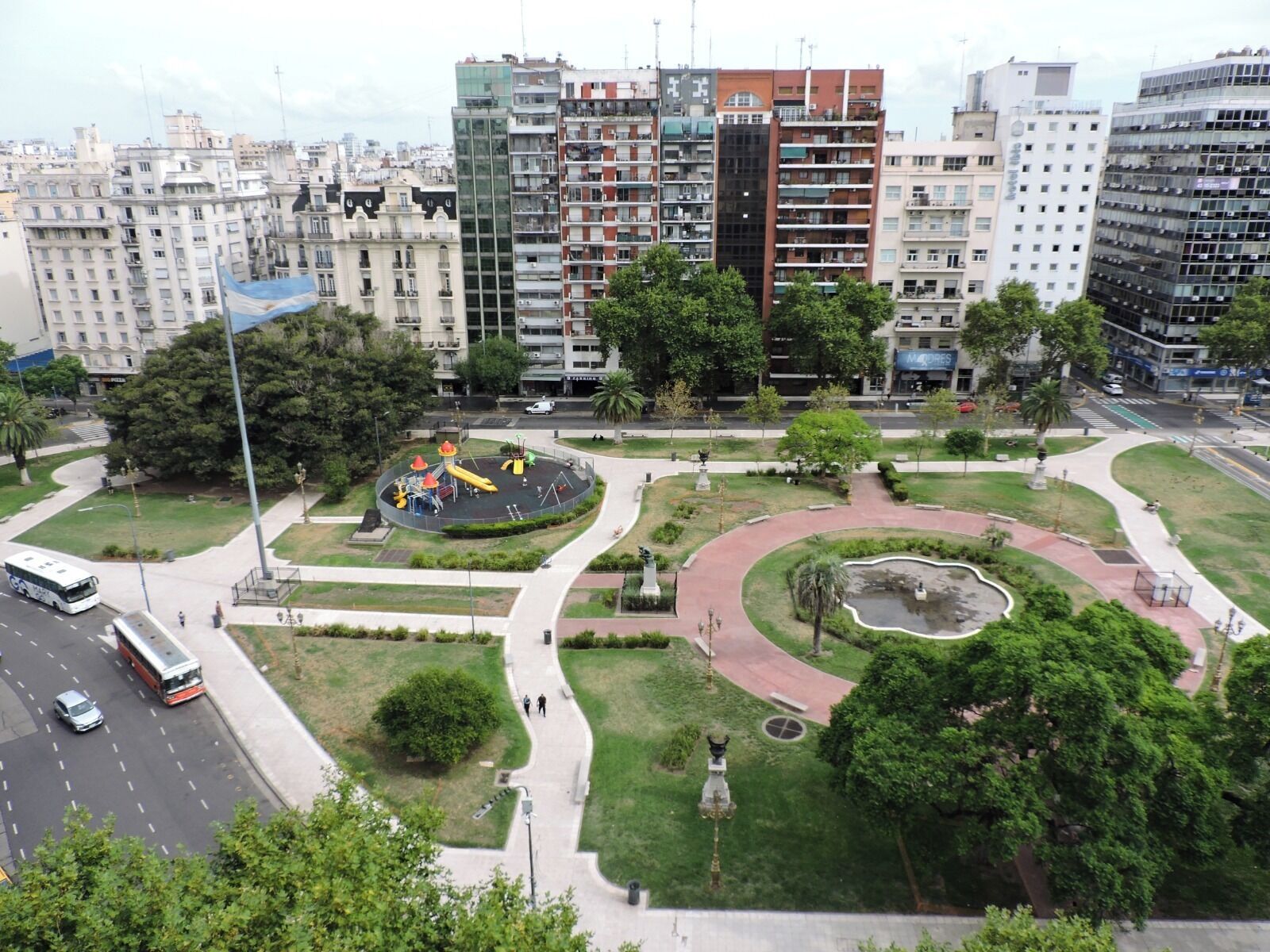 A park with playground equipment, a fountain, and a statue.
