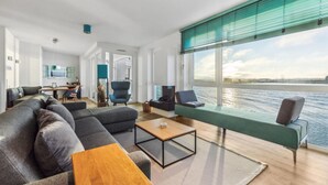 Un salon moderne avec un canapé, une table basse et une vue sur l’eau.
