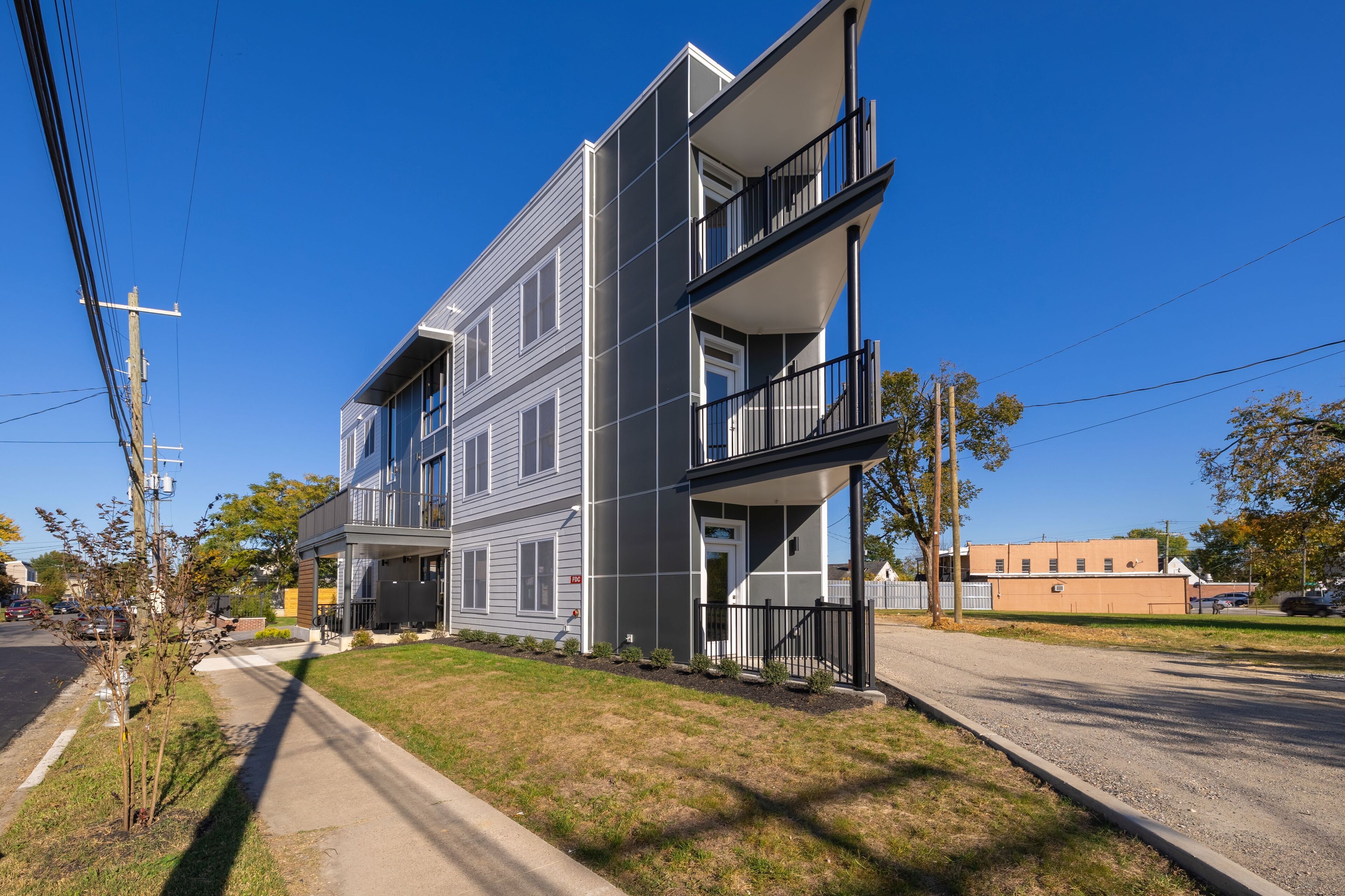A two-story residential building with a balcony on the second floor, a front porch, and a visible garage.