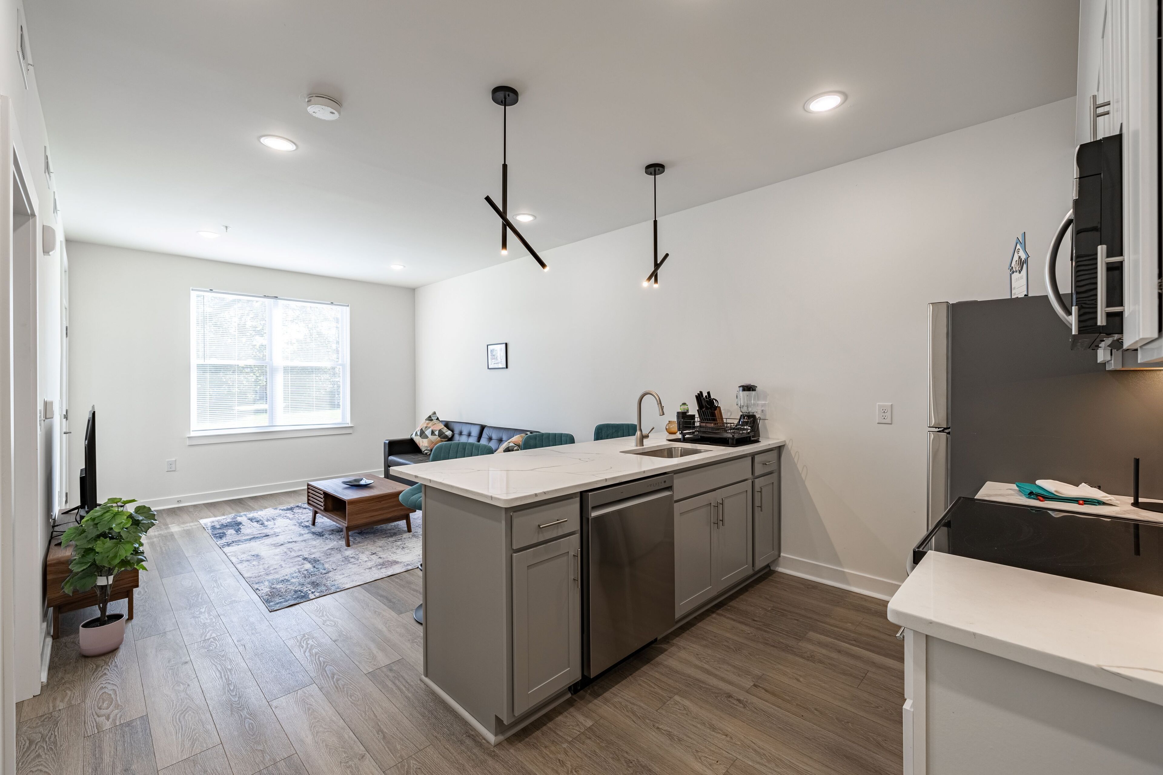 A modern kitchen with a central island, stainless steel appliances, and pendant lighting.