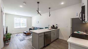 A modern kitchen with a central island, stainless steel appliances, and pendant lighting.