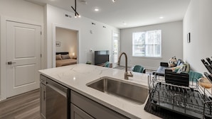 A modern kitchen with a large island, built-in dishwasher, and a black utensil rack. - Tourist Homes of Richmond Church Hill North (Richmond)