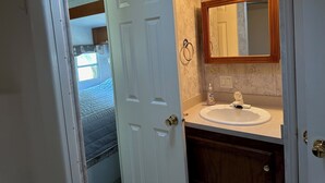 Un baño con una puerta blanca, un lavamanos, un espejo y una lámpara.