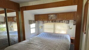 Un dormitorio con una cama grande, cabecera de madera y una ventana con persianas.