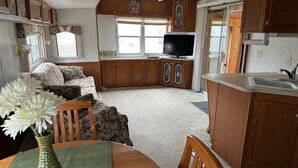 A compact RV interior with a dining area, kitchenette, and a TV. - Tranquil cabin with AC on charming Lake Sarah.   (Erskine)