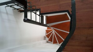 A spiral staircase with a wooden finish and metal railings.