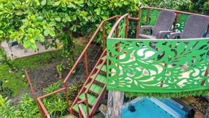 Una vasca idromassaggio con scaletta e sedie, immersa nel verde.