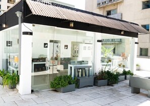 A modern outdoor café with glass walls, potted plants, and outdoor seating. - Moreno 820 Design Apartments (Buenos Aires)