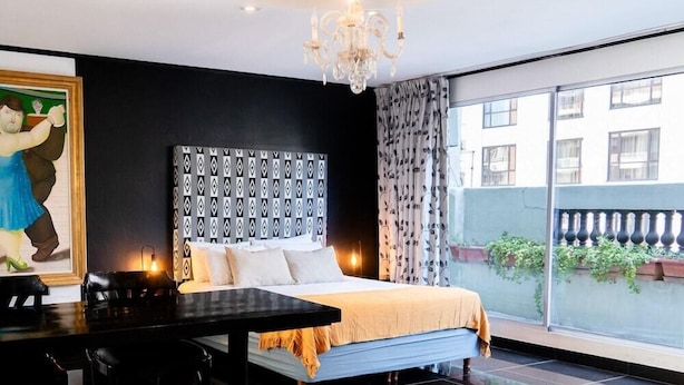 Une chambre avec un grand lit, un lustre, une table à manger et une vue sur l’extérieur.