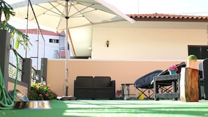 A covered patio area with a grill, outdoor seating, and a hose. - FX Hostel (Funchal)