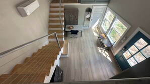 A modern kitchen with a central island, a dining area with a table and chairs, and a staircase leading to an upper level.