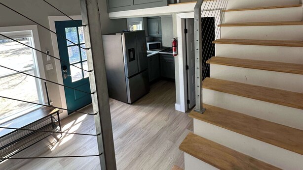 A modern kitchen with a built-in microwave, stainless steel refrigerator, and a small dining area.