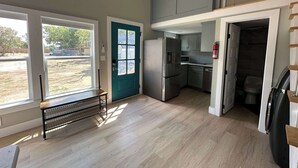 A compact kitchen with a built-in microwave, a stainless steel refrigerator, and a small sink.