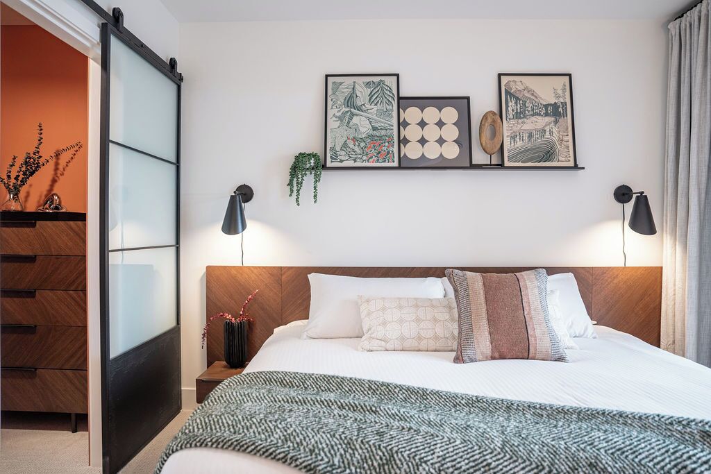 A modern bedroom with a bed, bedside tables, and wall-mounted artwork.