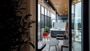 Un balcone moderno con vasca idromassaggio, zona salotto e vista sulle montagne.