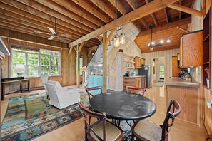 A spacious room with a large dining table, wooden ceiling beams, and a kitchen area with wooden cabinets. - Chautauqua Farmhouse & Cabin - Sleeps 12 - Streamside Retreat (Mayville)