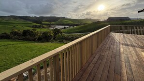 Une terrasse en bois offrant une vue sur des collines verdoyantes et une rivière.