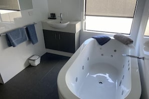 A modern bathroom with a freestanding bathtub, a sink, and a mirror. - Dolphin Lodge Albany - Self Contained Apartments at Middleton Beach (Middleton Beach)