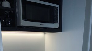 A compact kitchen with a microwave, kettle, and coffee maker.