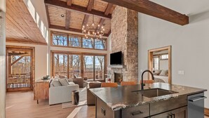 A spacious kitchen with a stone wall, wooden beams, and a large island with a sink.
