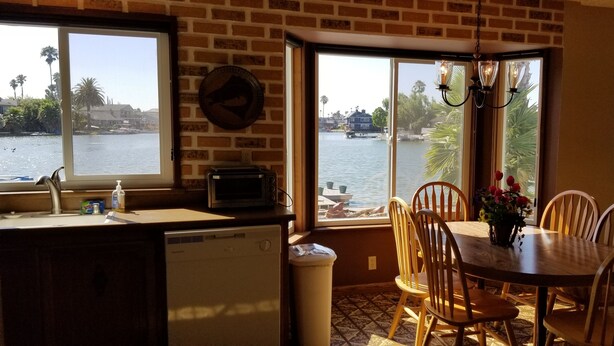 A kitchen with a view of a lake, a dining area with chairs and a table, and a dishwasher.