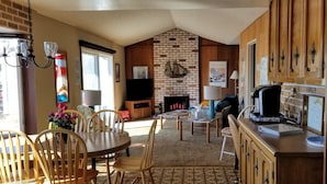 A cozy living room with a fireplace, wooden furniture, and a dining area.