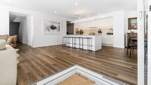 Une cuisine moderne avec des meubles blancs, un îlot central doté de tabourets et un coin repas avec une table et des chaises.