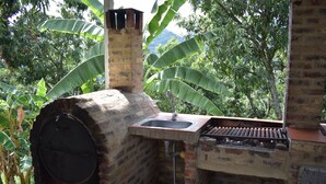 A brick oven with a sink and a chimney, surrounded by lush banana trees. - Finca el Paraiso Casa Loma, Tena (Cundinamarca)