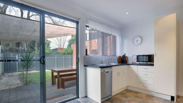 A modern kitchen with a sliding glass door leading to a patio area. - Beach & Pines Large 3Br House Glenelg Wifi BBQ (Glenelg South)