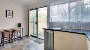 A kitchen with a dishwasher, a sink, and a window with curtains. - Beach & Pines Large 3Br House Glenelg Wifi BBQ (Glenelg South)