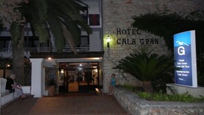 The entrance to Hotel Cala Gran with a stone facade and a signboard.