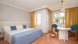 A bedroom with a bed, a small table, chairs, and curtains.