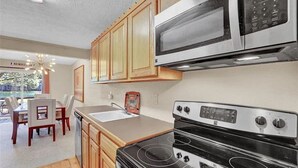 A kitchen with wooden cabinets, a microwave, an oven, and a sink.
