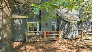 A rustic cabin with a wooden deck, a covered area, and a fenced-in space.