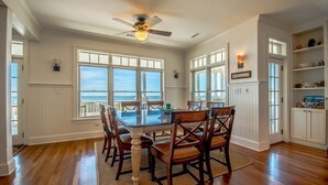 Uma sala de jantar com uma mesa grande, cadeiras de madeira e um ventilador de teto.