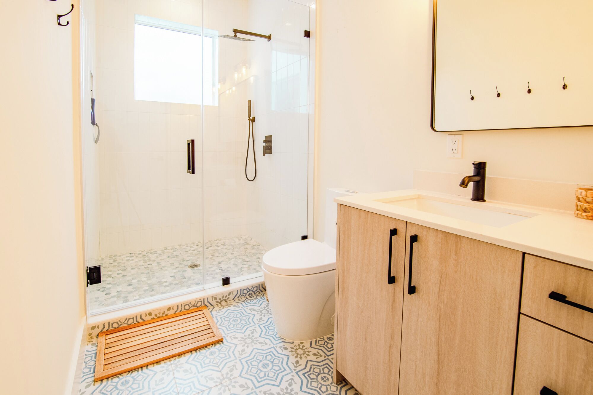 A modern bathroom with a glass-enclosed shower, a toilet, and a vanity with a sink and mirror.
