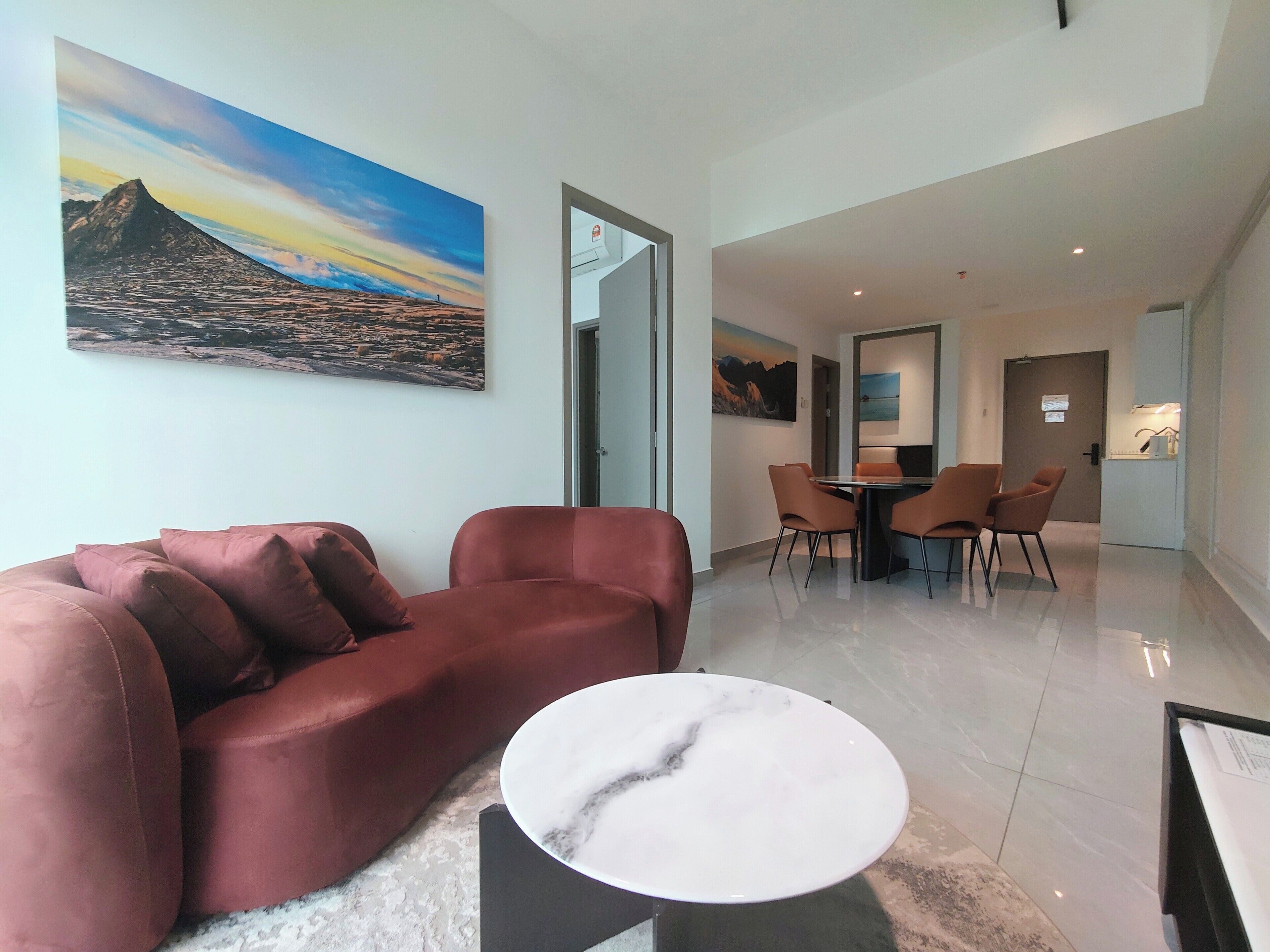 Una sala de estar moderna con un sofá rojo, una mesa de centro de mármol y un comedor con mesa y sillas.