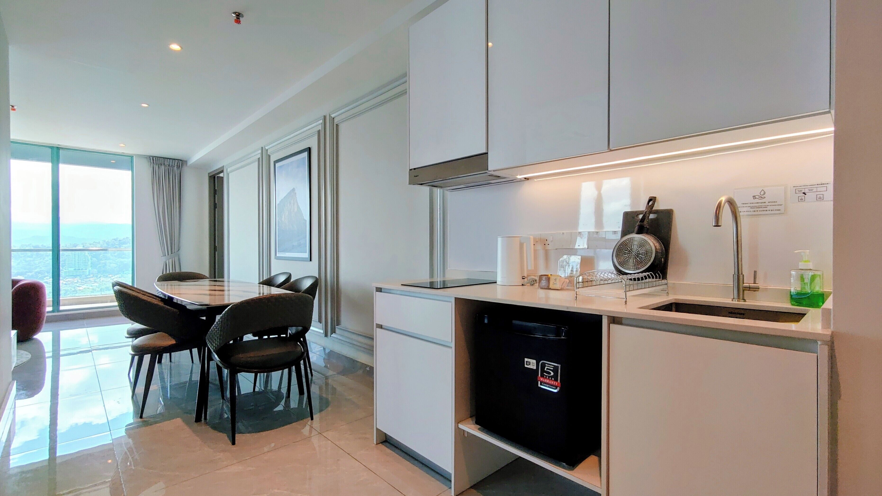 A modern kitchen with a dining area, large windows, and a view of the city.