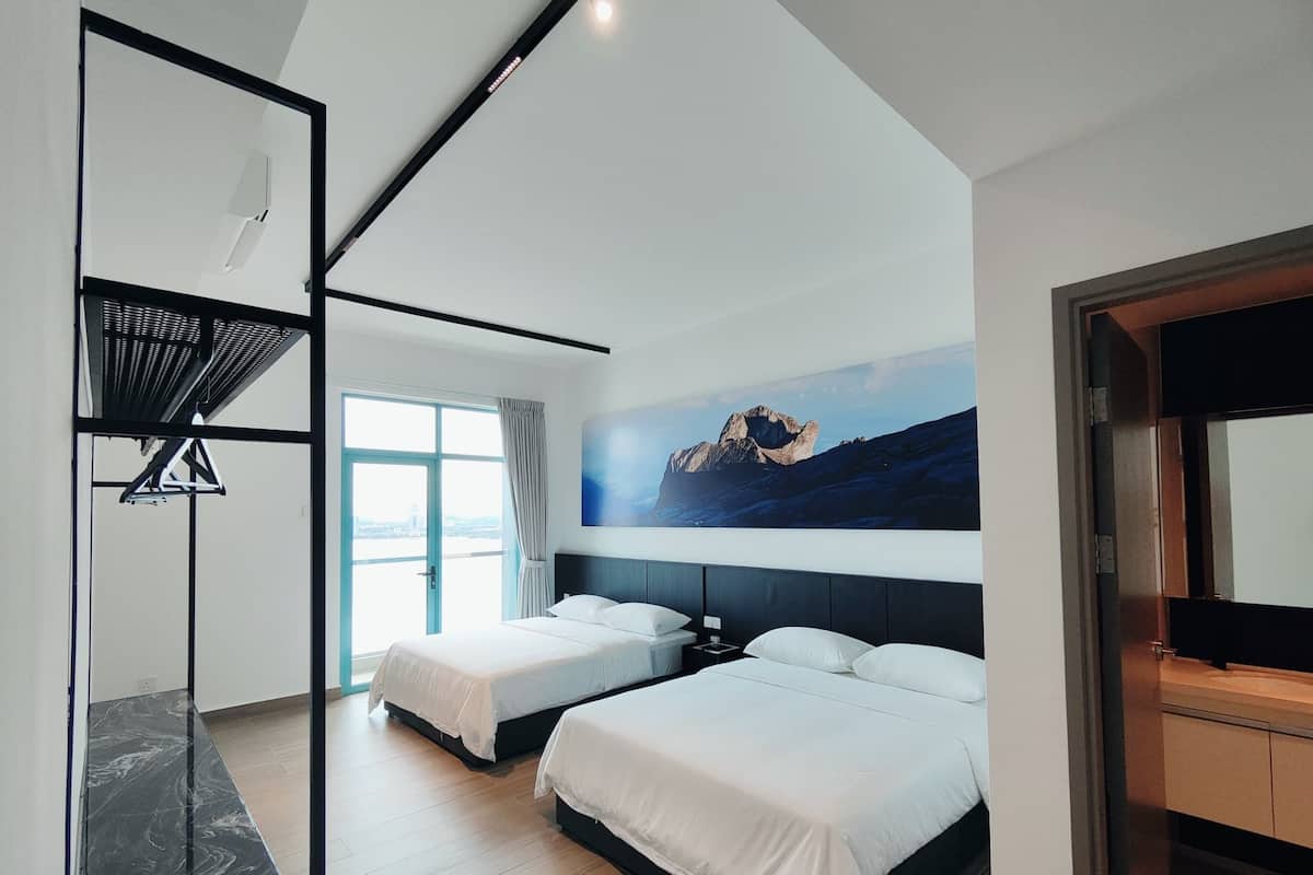 A modern hotel room with two beds, a large window, a painting of mountains, and a black-framed mirror.
