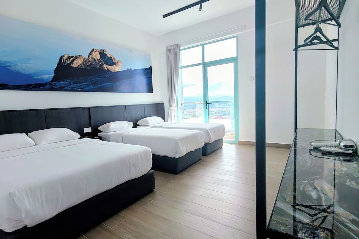 A hotel room with two beds, a large window with a city view, and a painting of a mountain landscape.