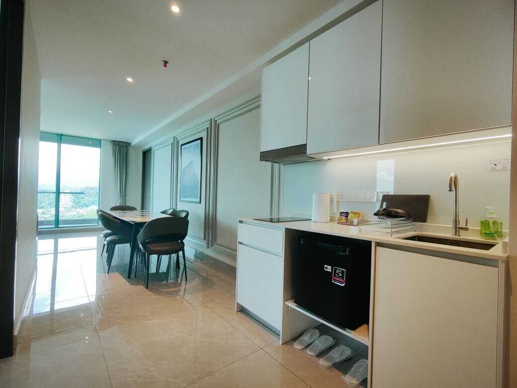 A modern kitchen with white cabinets, a built-in dishwasher, and a window overlooking a balcony.