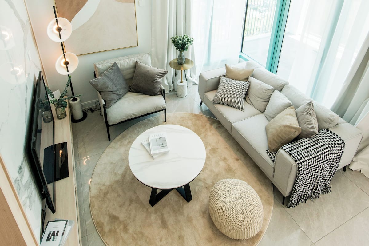 A modern living room with a white sofa, a round coffee table, and a large abstract painting on the wall.