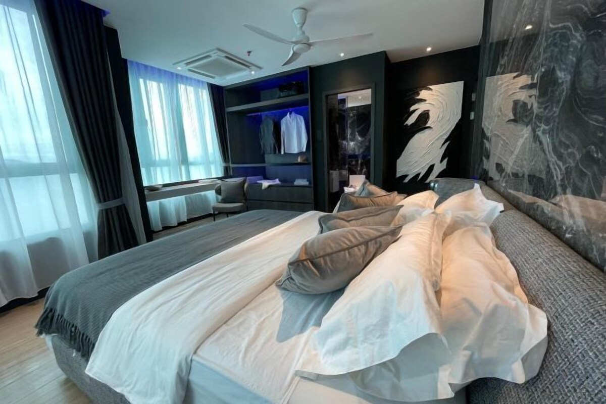 A modern hotel room with a large bed, a seating area, and a view of the city.