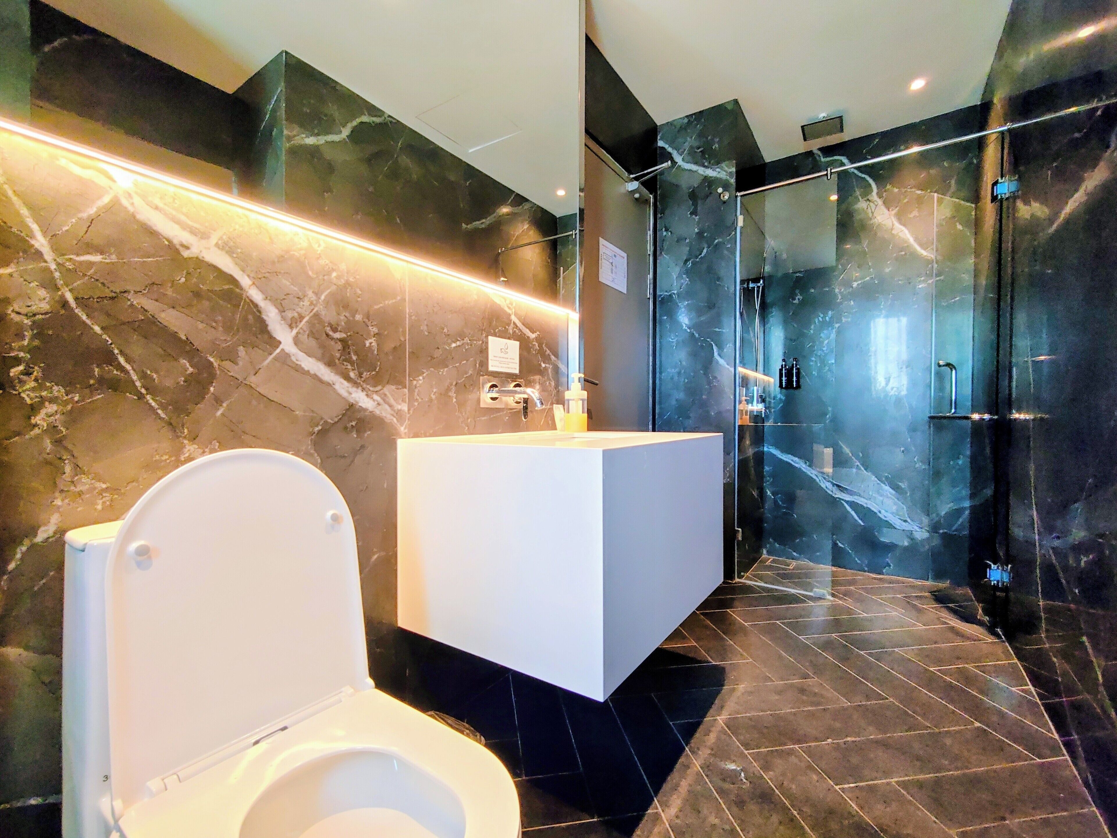 A modern bathroom with a toilet, a white vanity, and a glass-enclosed shower area.