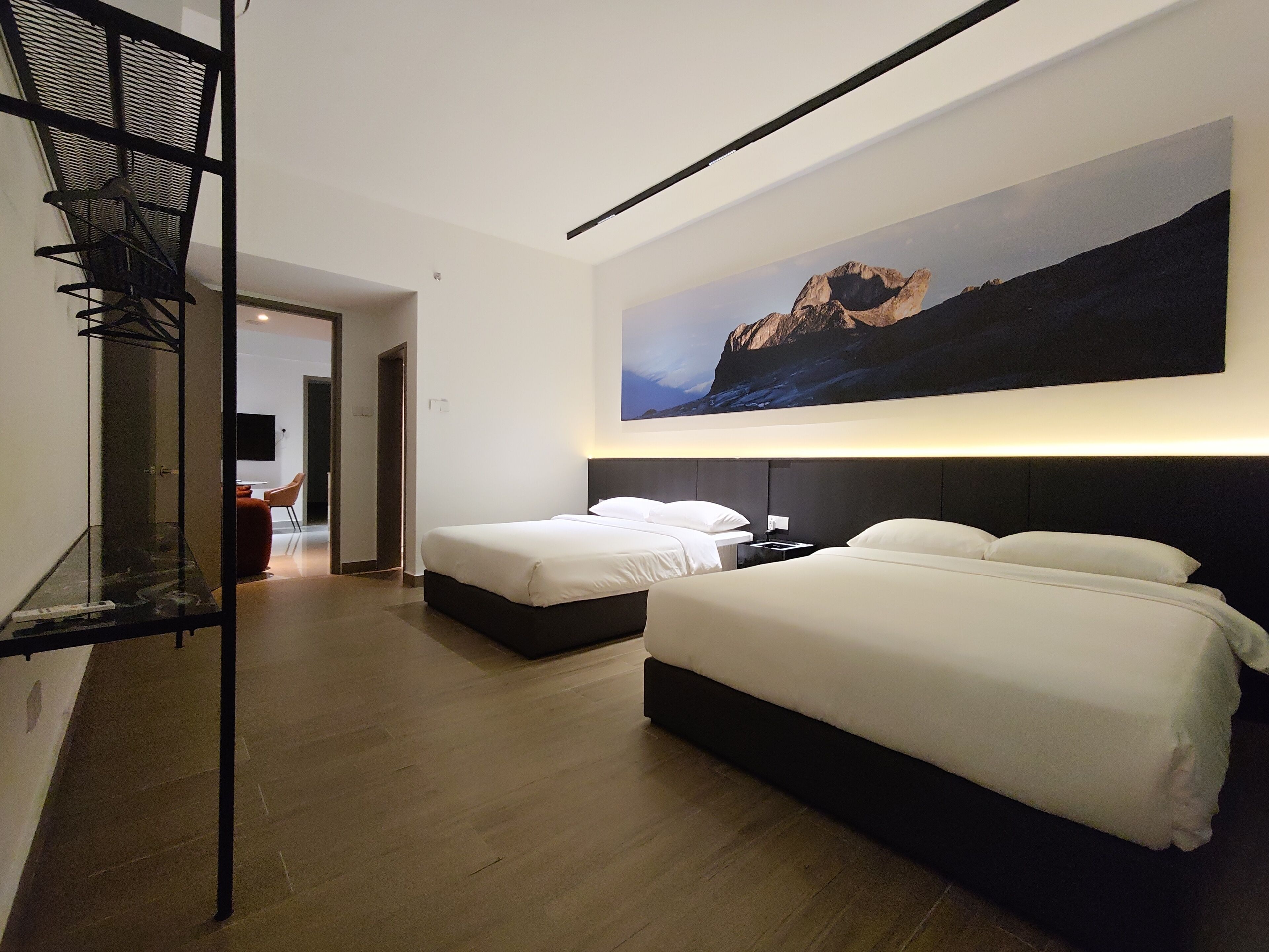 A hotel room with two beds, a large wall-mounted painting, and a wooden floor.