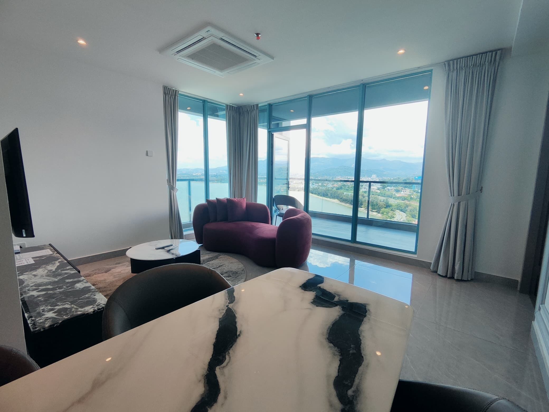 Habitación de hotel moderna con un amplio ventanal que ofrece una vista panorámica de una ciudad y montañas.