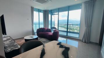 Habitación de hotel moderna con un amplio ventanal que ofrece una vista panorámica de una ciudad y montañas.