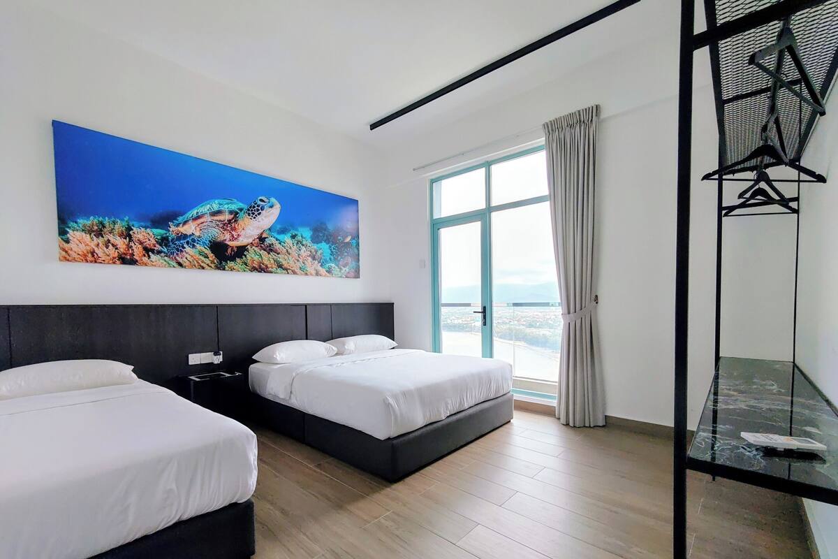 A modern hotel room with two beds, a large window with a view, and a painting of a sea turtle.